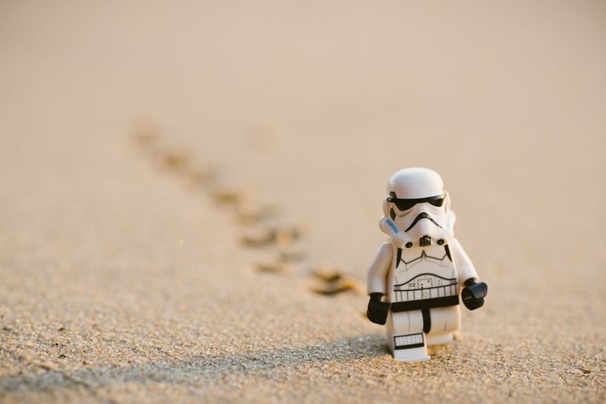 Star Wars Lego Stormtrooper in white suit walks towards the camera leaving footprints in the sand behind them