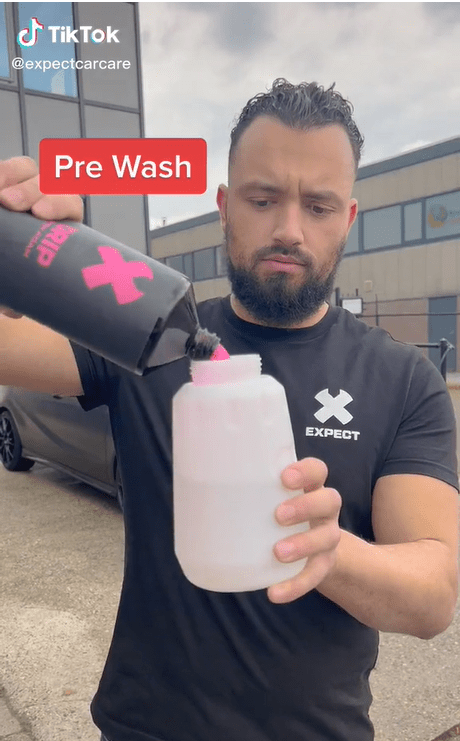 Man pours prewash cleaning liquid into a bottle for the camera